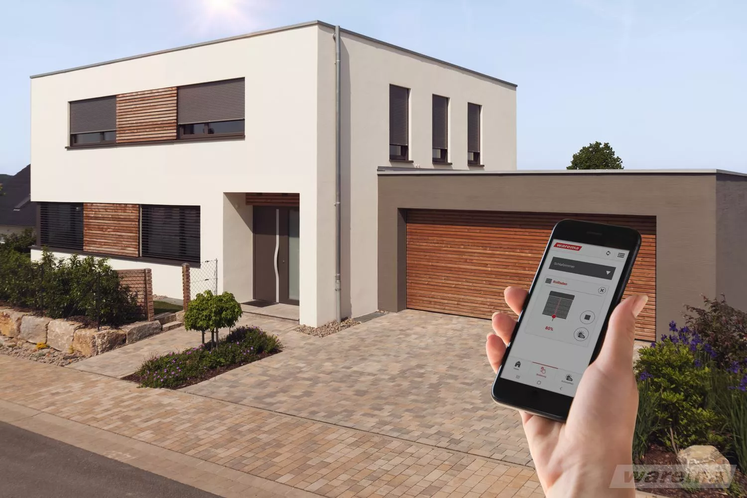 Blick auf ein Haus mit Rollläden, seitlich hält eine Hand ein Smartphone mit geöffneter App zur Steuerung der Rollläden.